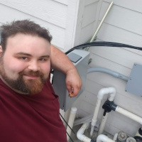 Chadwick Ferguson, Master Electrician and Co-Owner of Bright Haven Electric, smiling while working on an outdoor electrical panel installation.