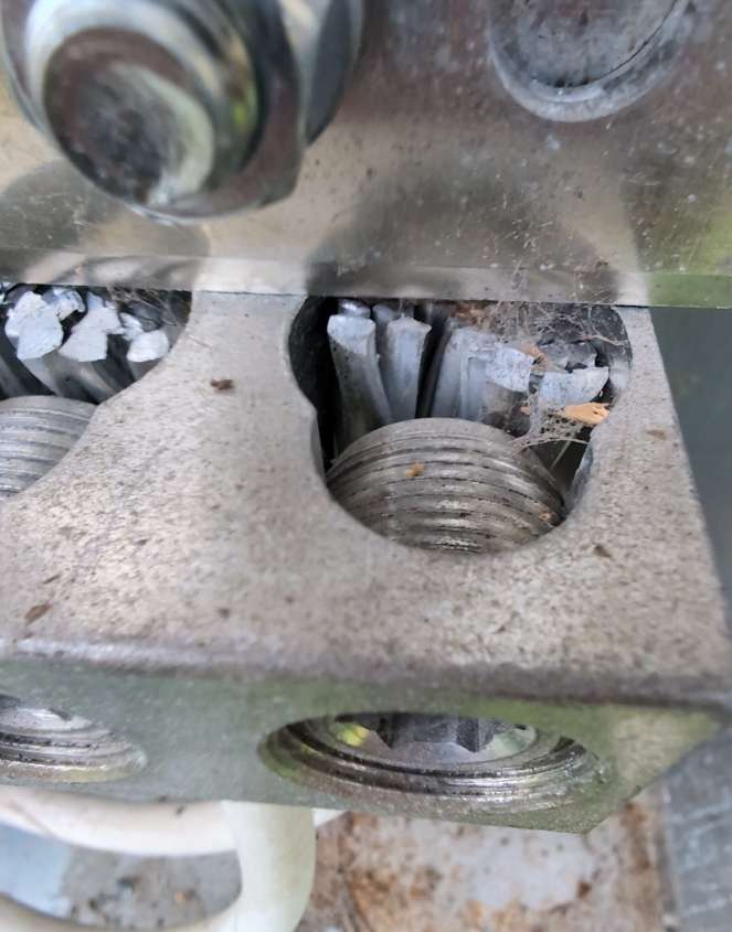 Untreated aluminum connections without oxide inhibitor — white aluminum oxide buildup and debris visible on bare conductor strands in mechanical lug